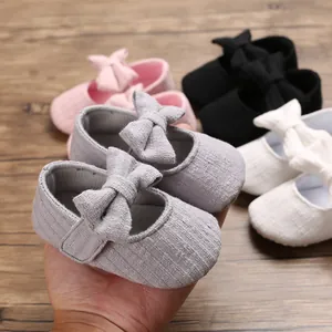 Close-up of grey soft sole baby walker shoe with a cute bow on a wooden background