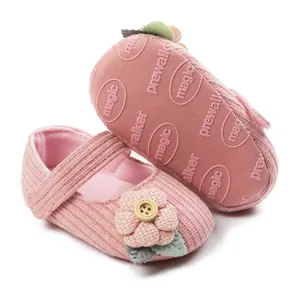 Detail view of pink knitted baby shoes with floral button and non-slip soles.