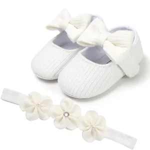 Primer plano de zapatos de punto para bebé blancos con lazo y diadema floral a juego