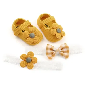 Detailed view of yellow knit baby shoes with floral accents and matching lace bow headbands