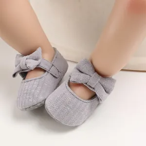 Close-up of soft-soled gray baby walker shoes with large bow and non-slip bottom.