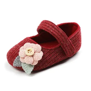 Close-up detail of red knit baby princess shoe with pink flower and wooden button