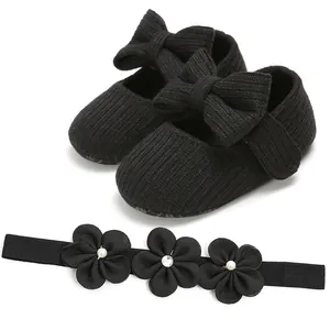 Detalle de zapatos de punto para bebé con lazos negros y conjunto de diadema de flores