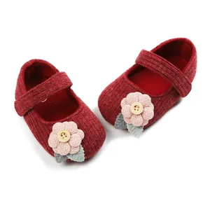 Detail of red knitted baby Mary Jane shoes with pink flower and button accents