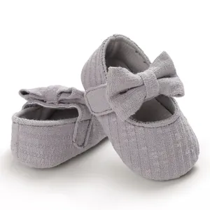 Close-up detail of soft grey ribbed fabric baby shoes with large bow decoration