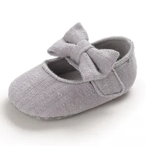 Close-up detail of grey baby princess shoe featuring large bow and textured fabric