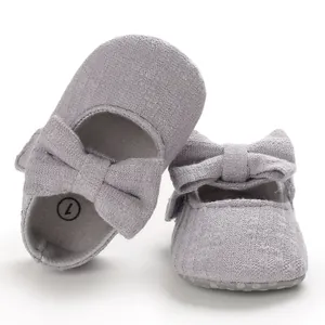 Close-up of grey infant soft sole walking shoes with large bow and knitted texture.