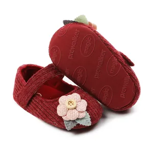 Close-up of red knit baby princess shoes with pink flower and non-slip sole detail