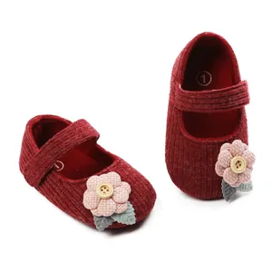 Detail view of burgundy baby knit princess shoes with pink flower and wooden button