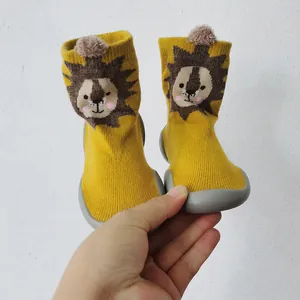 Dettaglio di scarpe a calzino per neonati con leone giallo e suola in gomma antiscivolo