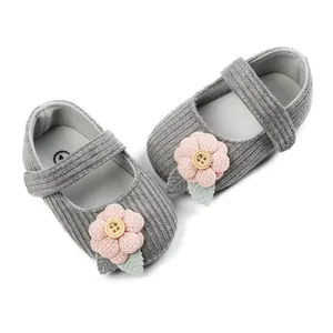 Detail of cute gray knit baby princess shoes with pink fabric flower and button.