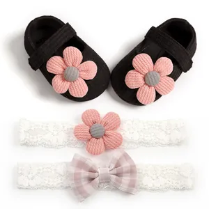 Detailed view of black knit baby girl shoes and lace headbands with pink flower accent