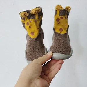 Primo piano di scarpe calzino per neonati a giraffa con suole in gomma morbida e pompon