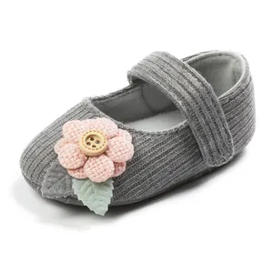 Detail view of grey knitted baby princess shoe featuring a pink flower and wooden button.