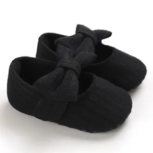 Detail view of black knitted baby walker shoes featuring a large decorative bow on top