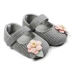 Soft grey knitted baby walking shoes featuring delicate pink fabric flower and wooden button detail