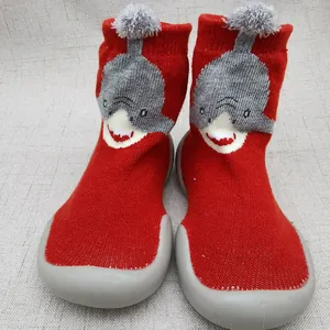 Dettaglio scarpe a calzino rosse per neonato con squalo cartone e suola in gomma grigia