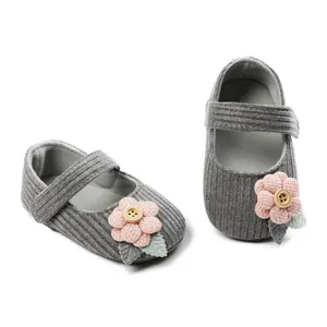Close-up view of cozy gray knit baby shoes with decorative pink flower and wood button