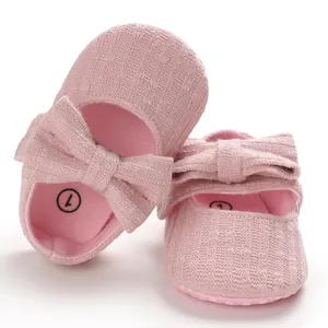 Detailed close-up of soft pink knitted baby girl walking shoes featuring a delicate bow