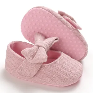 Detail view of pink baby shoes featuring soft non-slip dotted soles and a decorative bow