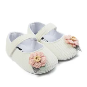 Detailed close-up showing white ribbed baby Mary Jane shoes with pink flower and button