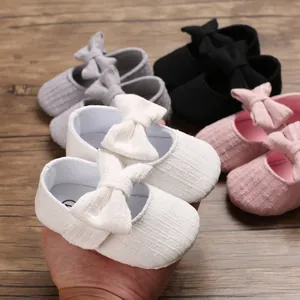 Close-up of white baby girl walking shoe with large bow knot and ribbed texture