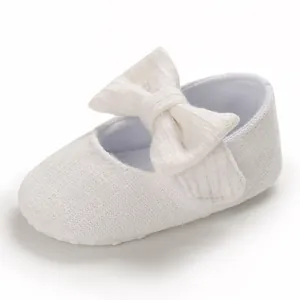 Close-up of white baby girl princess shoe with large bow and soft anti-slip sole