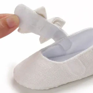 Close-up detail of white baby walking shoe showing hook and loop strap closure mechanism