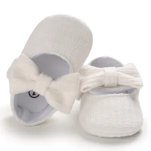 Close-up of white baby princess shoes with textured fabric and large bow detail