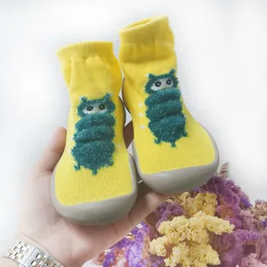 Dettaglio di scarpe a calzino gialle per neonati con un simpatico motivo a bruco verde
