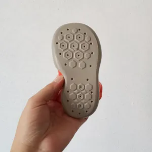 Vista dettagliata della suola antiscivolo esagonale traspirante per queste scarpe da neonato.