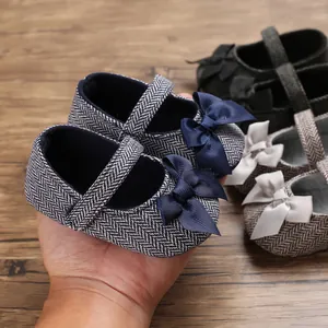 Nahaufnahme von Baby-Lauflernschuhen mit Fischgrätenmuster und blauer Schleife