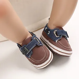 Dettaglio scarpe neonato in tela marrone con cinturini blu navy e suole morbide.