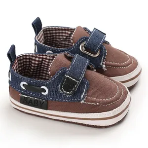Dettaglio di scarpine da neonato in tela marrone e denim con suola morbida antiscivolo