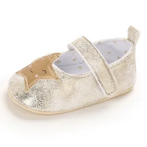 Detalle de zapato de bebé dorado con estrella sonriente y suela blanda para caminar.