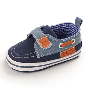 Primo piano di scarpe primi passi da neonato in denim blu scuro con suola morbida.