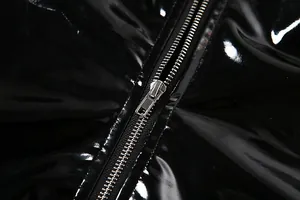 Gros plan détaillé du tissu en PU noir brillant et de la fermeture éclair métallique.