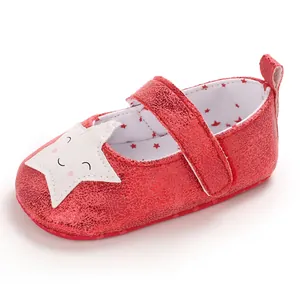 Detalle de zapatos rojos para bebé con parche de estrella sonriente y textura brillante.