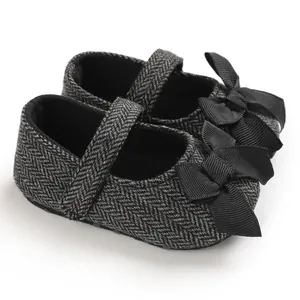 Detailansicht der grauen Baby-Lauflernschuhe mit Fischgrätmuster und Schleife.