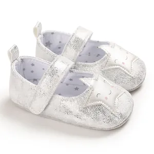 Primer plano de zapatos plateados para bebé con diseño de estrella sonriente y suela blanda