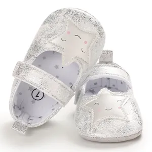 Primer plano de zapatos de bebé plateados con un diseño de estrella sonriente