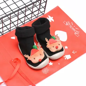 Primer plano de zapatos de Navidad negros para bebés con caras de renos de peluche