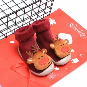 Vista detallada de calcetines zapatos rojos de Navidad para bebé con reno sobre fondo rojo