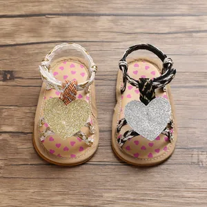 Close-up top view of adorable baby girl sandals with glitter heart and braided straps.