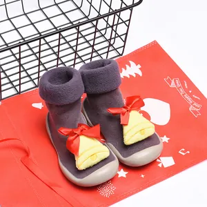 Detalle de zapatos calcetín navideños para niños con campana de felpa y lazo rojo