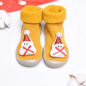 Primer plano de zapatos tipo calcetín navideños amarillos para bebé con muñeco de nieve