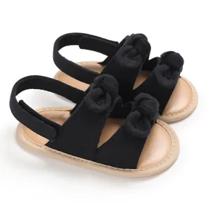 Vue détaillée de sandales de marche pour bébé noires avec nœuds mignons et semelles souples.