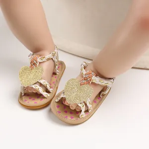 Close-up of baby girl sandals featuring glitter heart detail and braided straps