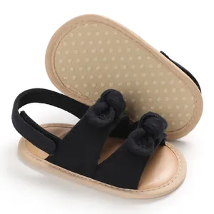 Vue détaillée de sandales en toile noire pour bébé avec semelles souples et jolis petits nœuds.