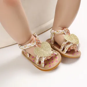 Detailed view of baby girl summer sandals featuring glitter gold heart and white braided straps